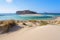 Scenery of sunny summer day with sand beach, turquoise sea and mountains. Place for tourists rest Balos lagoon, Crete island.