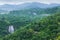 Scenery top view of beautiful waterfall in tropical forest, fresh mist, wild flowers with green mountains in rainy day. Khlong Lan