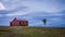 Scenic abandoned old red house in a remote area with a tree next to it