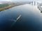 Scenic aerial cityscape of Kiev and river Dnipro at sunset. Tugboat supporting barge with sand bulk materials heading down river