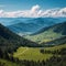 Scenic aerial landscape with green mountain vastness under cumulus clouds in blue sky in changeable weather.