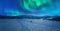 Scenic aerial night skies panorama on frozen lake, mountains with snow mobile traces, northern green lights. Scandinavian night