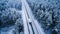 Scenic aerial view of motorhome driving on snowy road through winter coniferous forest