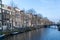 Scenic Amsterdam canal with traditional tall wonky crooked houses along the waterfront.