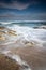 Scenic atlantic coastline with waves in motion around rocks on sandy beach in long exposure, bidart, basque country, france