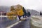 Scenic autumn view with the first snow on a dirt wet road in the mountains, trees and forest in the snow and hoarfrost on the