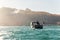 Scenic back view of fisherman angler enjoy fishing with rods on motor boat ship at clean green blue azure water harbor