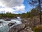Scenic background with raging mountain river flows through stone rapids among the deserted rocks and forests of northern Norway.