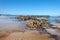 Scenic beach landscape with an expanse of small rocks, sand, and shimmering water in  South Africa