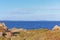 A scenic beautiful view of a Scotish wild seaside with majestic choppy blue sea with mountains summit in the background and grassy