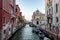 Scenic canal with bridge and ancient buildings with potted plants in Venice, Italy