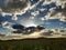 Scenic cloudscape against the blue sunny sky over the road and field