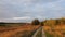 Scenic countryside landscape with rural dirt road across the wilderness. Autumn panoramic view with multiple birds flying