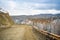 Scenic early spring view with snowy dirt road through the pass, green larch trees, snow and forest on the slopes against