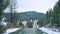 Scenic early spring view with snowy dirt road through the pass, green larch trees, snow and forest on the slopes against