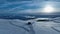 Scenic fly over snow mobile with carriage trailer, aerial video of winter sunset in lifeless snowy mountains. The shot is taken