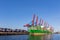 Scenic front giant cargo container ship loading Hamburg city port harbour seaport cranes on clear blue sky day