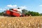 Scenic front view Big powerful industrial combine harvester machine reaping golden ripe wheat cereal field on bright