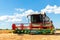 Scenic front view Big powerful industrial combine harvester machine reaping golden ripe wheat cereal field on bright