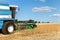 Scenic front view Big powerful industrial combine harvester machine reaping golden ripe wheat cereal field on bright