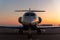 Scenic front view modern luxury expensive private jet plane parked airport taxiway hangar warm colorful dramatic evening