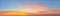 Scenic golden orange clouds against azure sky just before sunrise. Panoramic shot of bright dawn sky. Beautiful pastel colored