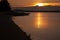 Scenic golden sea sunset with dark volcano in distance island with colorful orange heaven and sunbeams reflection in water.