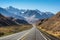 scenic highway with towering mountain range in the background