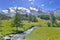 scenic ladscape in alpine mountain snowy and greenery meadow with a little river
