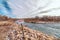 Scenic lake landscape on a cloudy day with snow on the rocky shore in winter