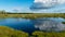 Scenic landscape with blue bog lakes surrounded by small pines and birches and green mosses on a summer day with blue skies and.