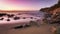 Scenic landscape of a calm rocky beach during colorful sunset