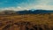 Scenic landscape with expansive grassland and distant mountains under a blue sky with clouds