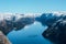 Scenic landscape of lake with the rocky shore with mountains with snowy peaks. Top view of the Pulpit Rock, Preikestolen