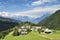 Scenic landscape with little alpine village on green hill