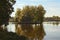 Scenic morning view of island with abandoned house and trees in the middle of the lake. Autumn landscape. Village of Old Solotvin