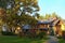 Scenic nature landscape of large wooden cottage in forest. Green grass on front yard. View through tree trunks.