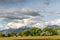 Scenic nature with trees and snow peaked mountain towering over a vast field