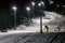 Scenic night view of illuminated snowy ski track with chair ski lift. Night skiing service at Sochi Gorky Gorod winter mountain re