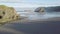 Scenic panoramic aerial drone view of flight above ocean and remote beach in Western USA with rocky cliff coastline and sand beach