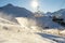 Scenic panoramic view of alpine peaks with ski lift ropeway on hilghland mountain winter resort and snow making machines on bright