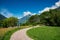 Scenic pathway winds through a lush meadow, offering a stunning view of the majestic mountains.