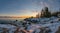 Scenic Remote view of Winter Sunset Over Sea with Icy and Snowy coastline, very big stones, Northern Sweden, Baltic region