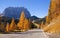 Scenic roadway in Dolomite Alps with beautiful yellow larch trees and Sassolungo mountain on background.