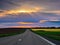 Scenic rural road stretching into the horizon, illuminated by a vibrant, picturesque sunset