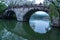 Scenic scenery with a reflection of a semi circular stone bridge stretching over a mirror lake