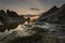 Scenic shot of a calm rocky hidden coast with the golden evening sun setting behind clouds