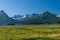 Scenic shot of the Chugach Mountains across the Matanuska River and a grass field in Valdez, Alaska