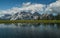 Scenic shot of a mountain range partially covered in snow in front of a still lake