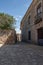 Scenic shot of a narrow empty street with an old-fashioned house from the right and a tree